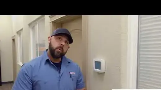 Associated Heating & Air Conditioning technician showing how to work a smart thermostat